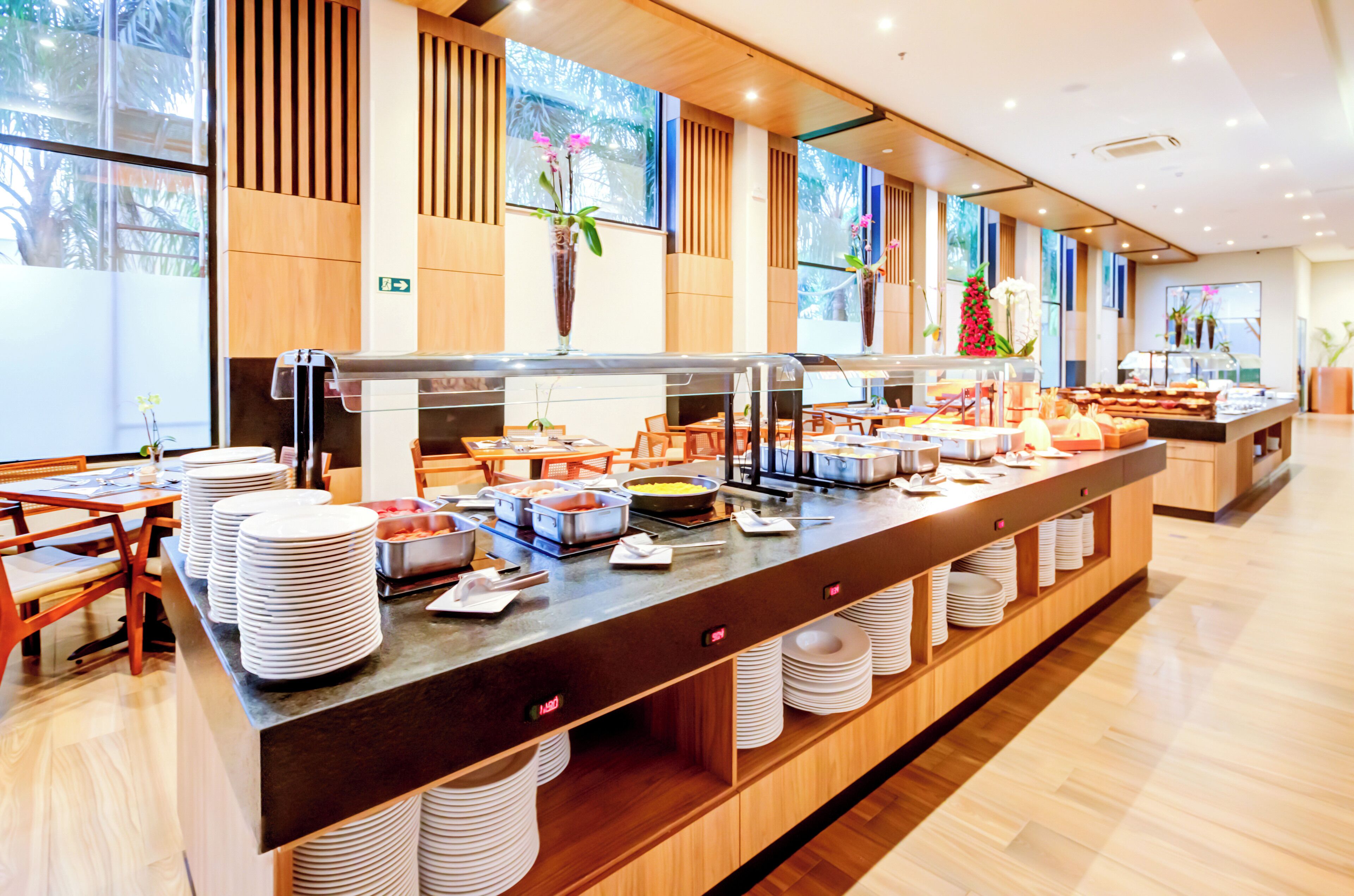 A buffet setup with multiple food stations, wooden paneling, and large windows.