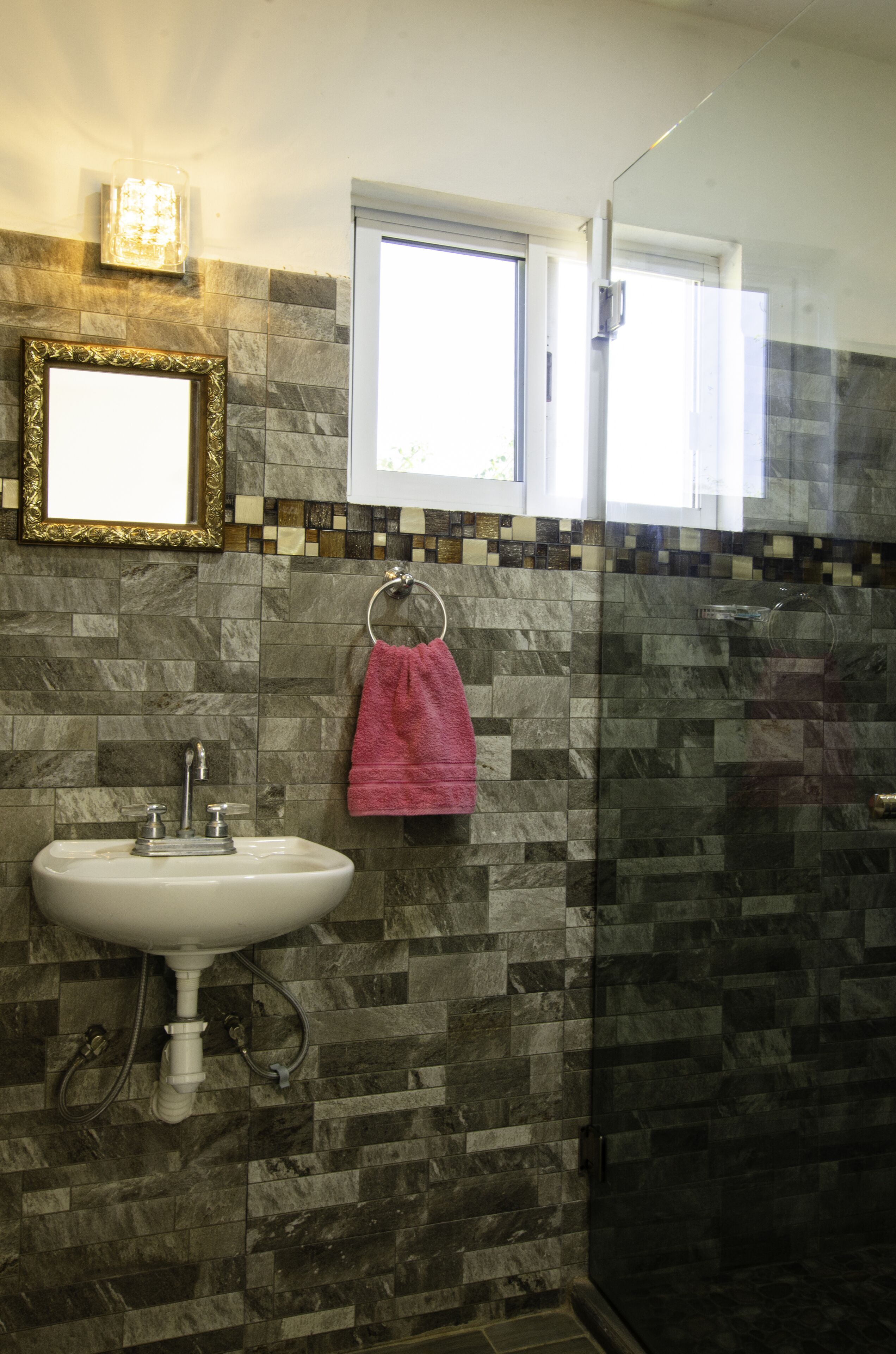 Une salle de bain équipée d’un lavabo, d’un miroir, d’une fenêtre et d’un espace douche.