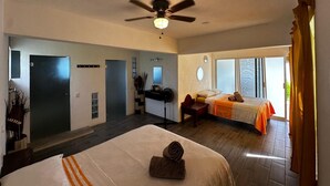 Habitación de hotel con dos camas, un escritorio, un ventilador de techo y vistas al exterior.