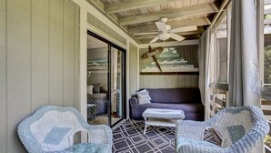 A covered porch with wicker furniture, a ceiling fan, and a couch with a 'Beach' sign. - Central Oasis: Pool, Tennis, Screened Porch Gem! (Fernandina Beach)
