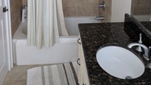 A bathroom with a bathtub, a shower curtain, a sink, and a mirror.
