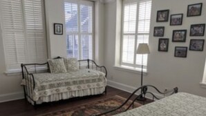 A bedroom with a bed, a chair, a rug, and a window with blinds.