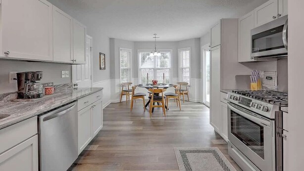 A modern kitchen with white cabinets, a central island with chairs, a built-in oven, and a large window. - CHAS, SUMMRVLL/NEXTON Comfort  Near Everything! (Summerville)