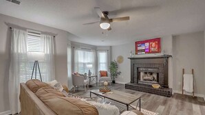 A living room with a sofa, coffee table, fireplace, and a ceiling fan. - CHAS, SUMMRVLL/NEXTON Comfort  Near Everything! (Summerville)