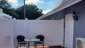 Eine Terrasse mit Backsteinboden, zwei schwarzen Stühlen und einem kleinen Tisch.