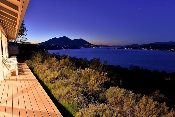 Une terrasse en bois donnant sur un lac, avec des montagnes en arrière-plan.