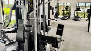 A gym with various exercise machines, a bench, and a TV screen.