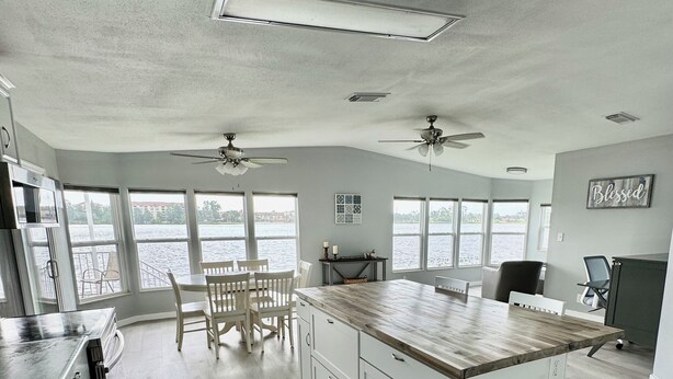 A spacious kitchen with a large island, white cabinetry, and a view of a body of water through large windows.
