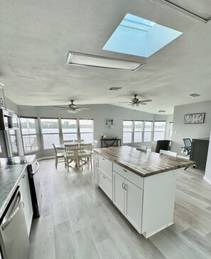 A spacious kitchen with a large island, white cabinetry, and a view of a body of water through large windows. - 2-bedroom home 5 miles to Disney on Lake. Four Corners. Vista Del Lago amenities (Winter Garden)
