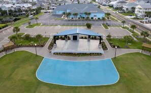 A hotel with a blue roof, a swimming pool, and a parking lot.