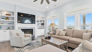 A modern living room with a fireplace, a large flat-screen TV, and a sofa set. - Beach Please! (Ocean Isle Beach)