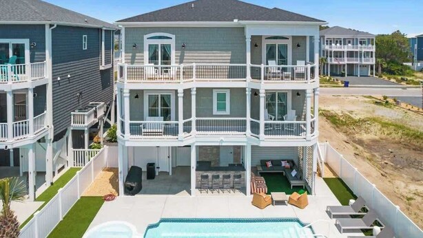 A multi-story residential building with a pool, outdoor seating, and a covered patio area. - Beach Please! (Ocean Isle Beach)
