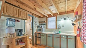 A compact kitchen with wooden cabinets, a microwave, a sink, and a fire extinguisher. - Cabins at Brush Creek Mtn-Bear Den (Del Rio)