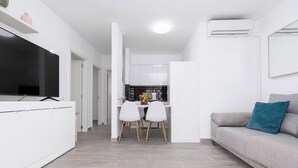 Um espaço de estar moderno e minimalista com cozinha, sala de jantar e sofá.