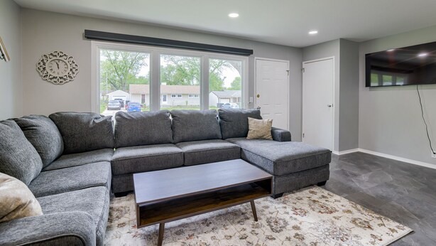 A modern living room with a grey sectional sofa, a wooden coffee table, and a patterned rug. - Hamilton in heart of Omaha! Multi family and group friendly! The perfect space!! (Omaha)