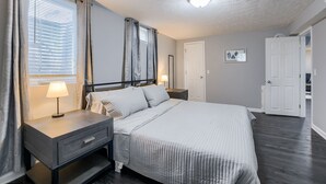 A bedroom with a bed, bedside tables, a lamp, a window with curtains, a door, and a ceiling light. - Hamilton in heart of Omaha! Multi family and group friendly! The perfect space!! (Omaha)