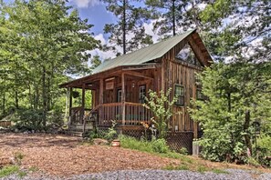 Eine rustikale Holzhütte mit Veranda, umgeben von dichtem Wald.