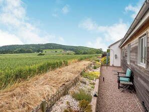 A patio with a view of a field and hills, wooden deck, and a chair. - 1 bedroom accommodation in Herford (Herford)
