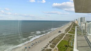 Une vue sur la côte, avec une plage, l’océan et, au loin, des immeubles de grande hauteur.