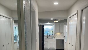 A modern kitchen with white cabinets, a black refrigerator, and a wooden floor. - Amazing waterfront home on Palma Sola Bay, a bicycle ride to  Anna Maria Island. (Bradenton)