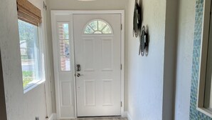 A hallway with a white door, a textured wall, a hanging light fixture, and a woven rug. - Amazing waterfront home on Palma Sola Bay, a bicycle ride to  Anna Maria Island. (Bradenton)