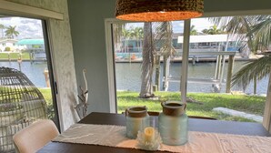 A dining table with a view of a water body and palm trees outside. - Amazing waterfront home on Palma Sola Bay, a bicycle ride to  Anna Maria Island. (Bradenton)