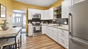 A modern kitchen with white cabinets, stainless steel appliances, and a wooden floor. - Trendy Fishtown Mid-Century Modern Inspired Home (Philadelphia)
