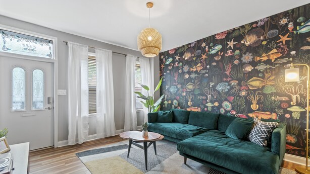 A living room with a green sofa, a round coffee table, and a large fish-themed wall mural. - Trendy Fishtown Mid-Century Modern Inspired Home (Philadelphia)