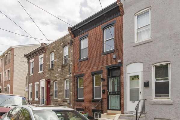 A row of townhouses with brick facades, white-framed windows, and a red door.