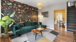 A living room with a green sofa, a round wooden coffee table, and a large mural of underwater scenes on the wall. - Trendy Fishtown Mid-Century Modern Inspired Home (Philadelphia)