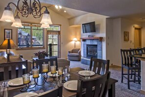 Enjoy meals in this stylish dining area with a fireplace, television, and window offering a view of the outdoors.