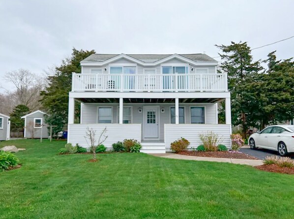 A two-story house with a front porch, a garage, and a small garden. - Beautiful 3 bedroom house by the ocean (Fairhaven)