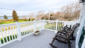 En overdækket terrasse med hvid gelænder, en gyngestol og en plantekasse.
