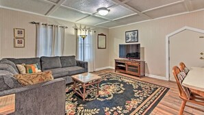 Uma sala de estar com sofá, mesa de centro, rack para TV e mesa de jantar.