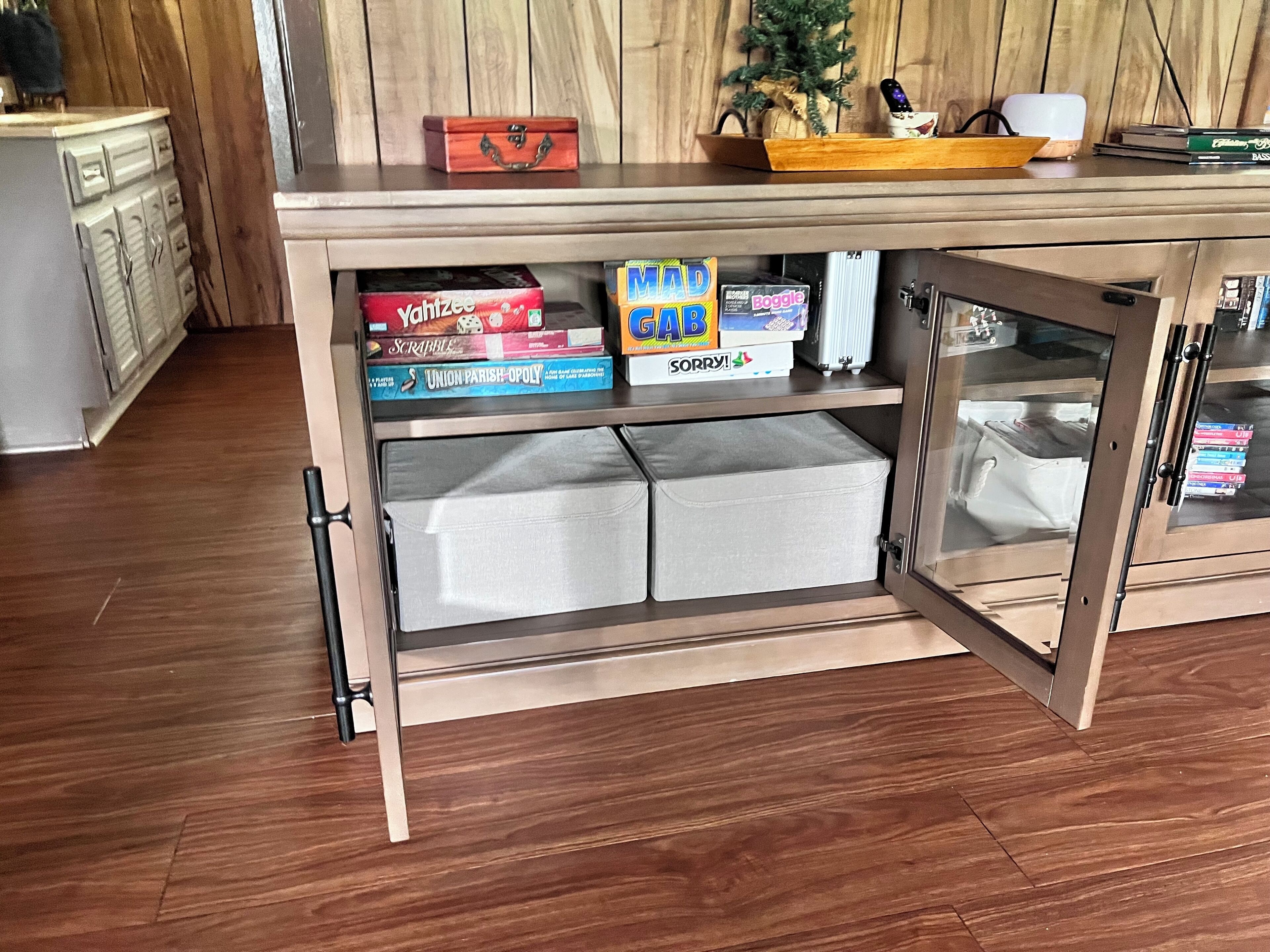 A wooden cabinet with shelves holding board games and storage boxes.