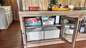 A wooden cabinet with shelves holding board games and storage boxes.