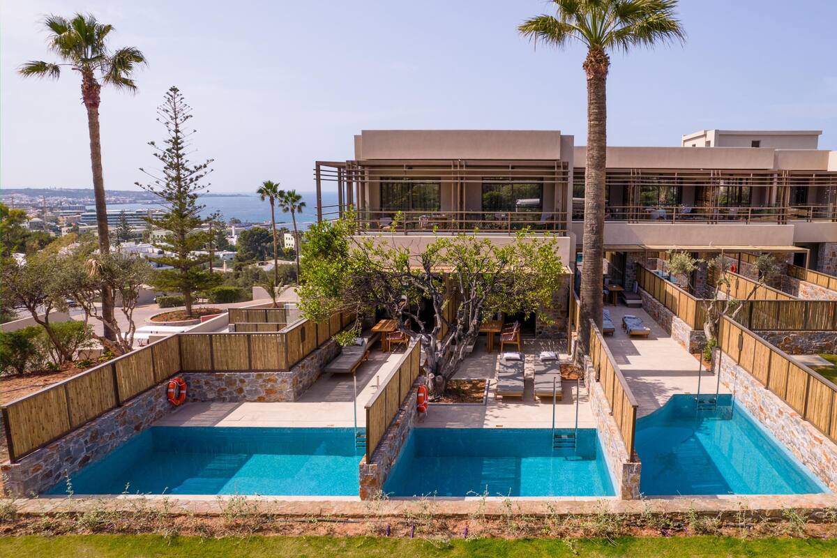 A modern hotel with a rooftop pool area, outdoor seating, and a view of the sea.