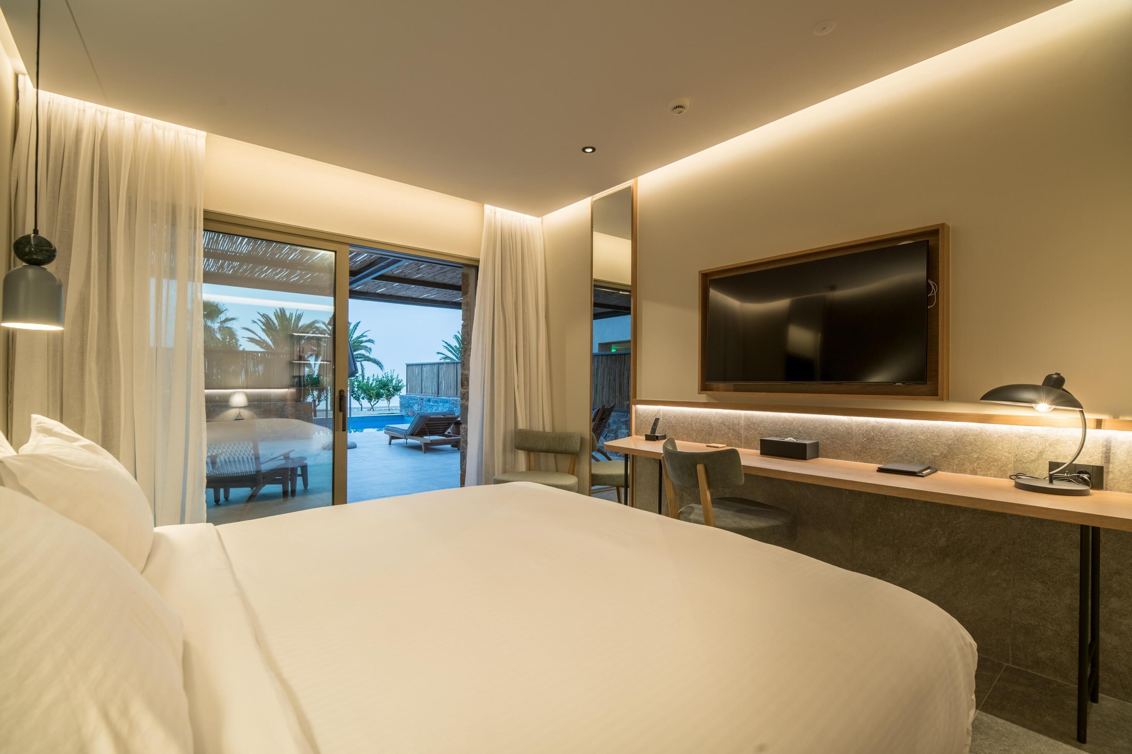 A modern hotel room with a large bed, a desk, and a TV.