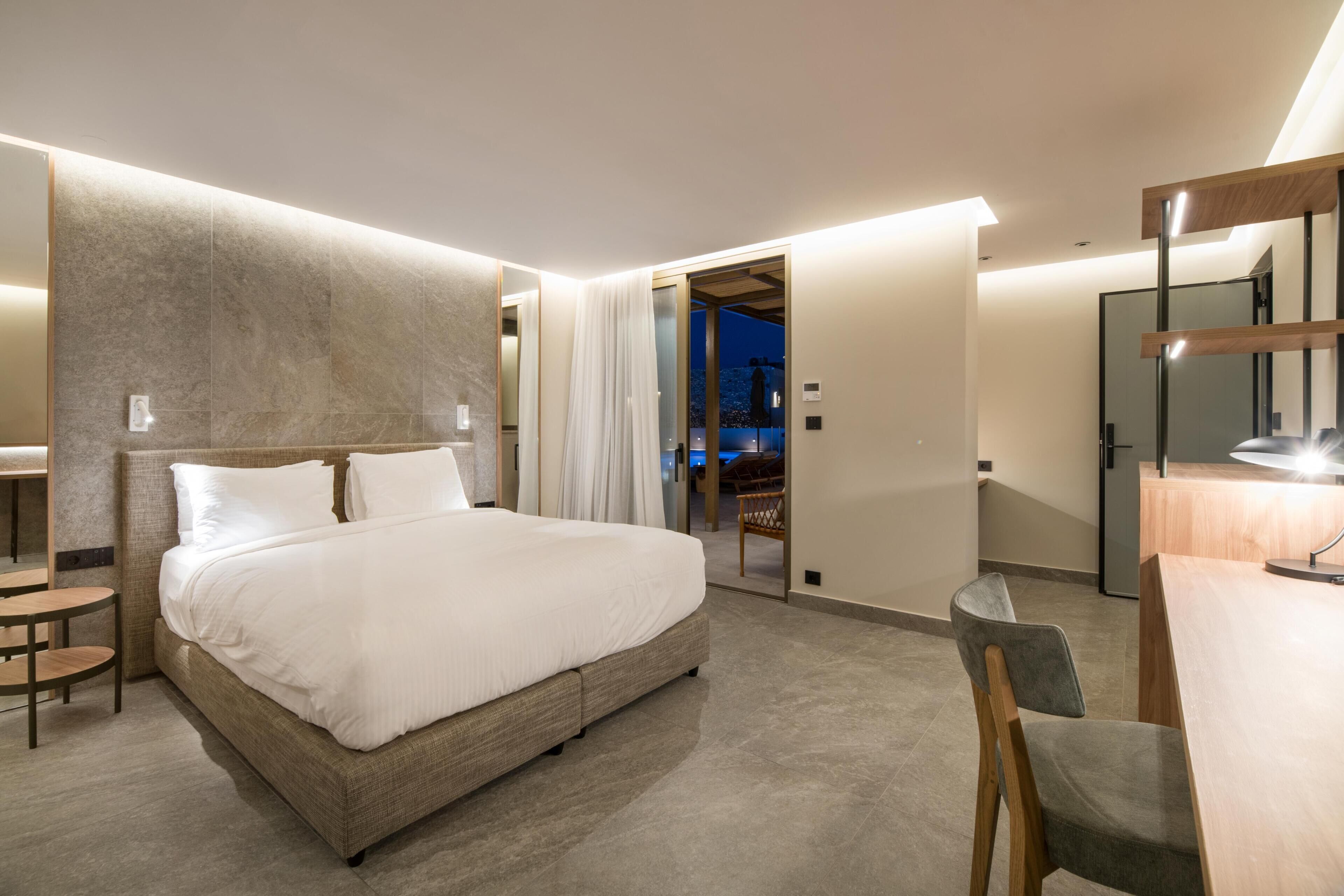 Una habitación de hotel moderna con una cama grande, un escritorio y un espejo.