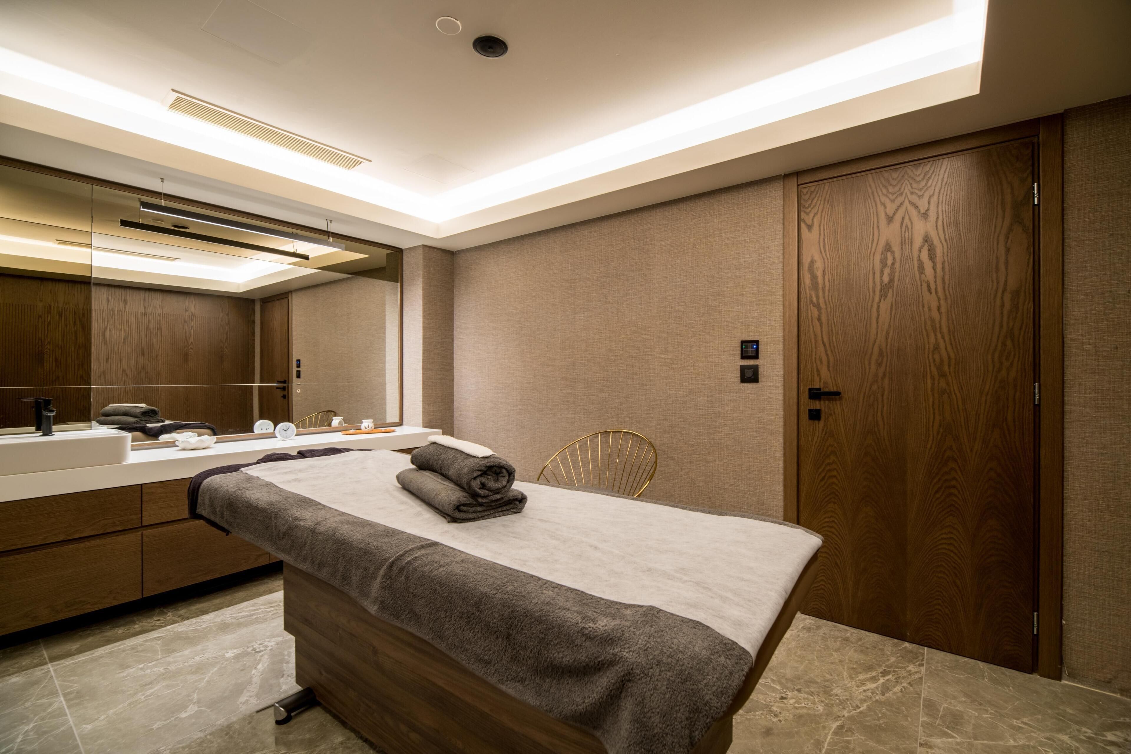 Un baño moderno con tocador de madera, un espejo grande y una mesa de masajes.