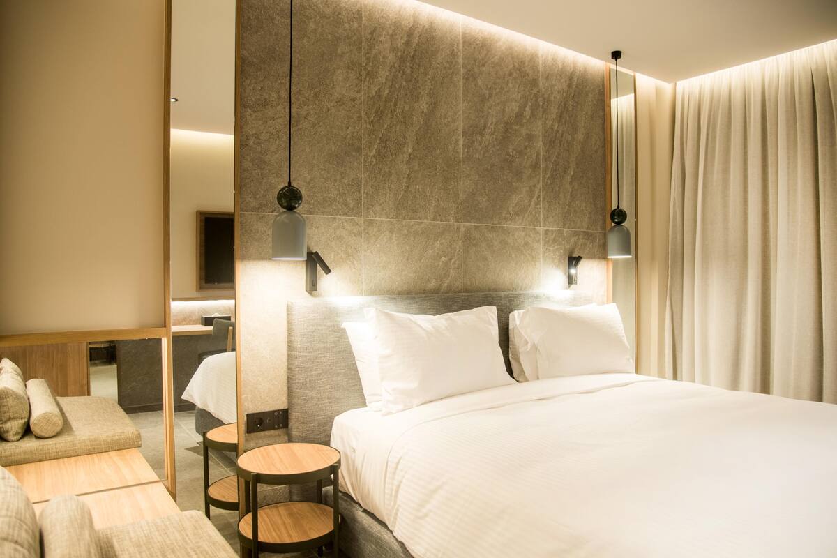 A modern hotel room with a large bed, a small seating area, and a television.