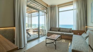 A modern living room with a sofa, a coffee table, and a view of the sea.