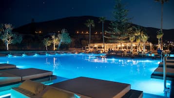 Een buitenzwembad, parasols bij het zwembad en ligstoelen