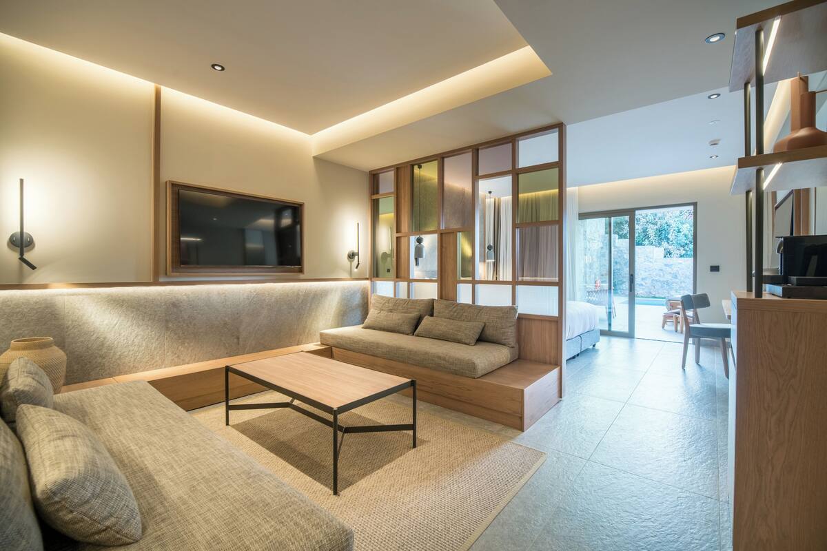 A modern living room with a sofa, coffee table, and a TV. There is a sliding door leading to a balcony.