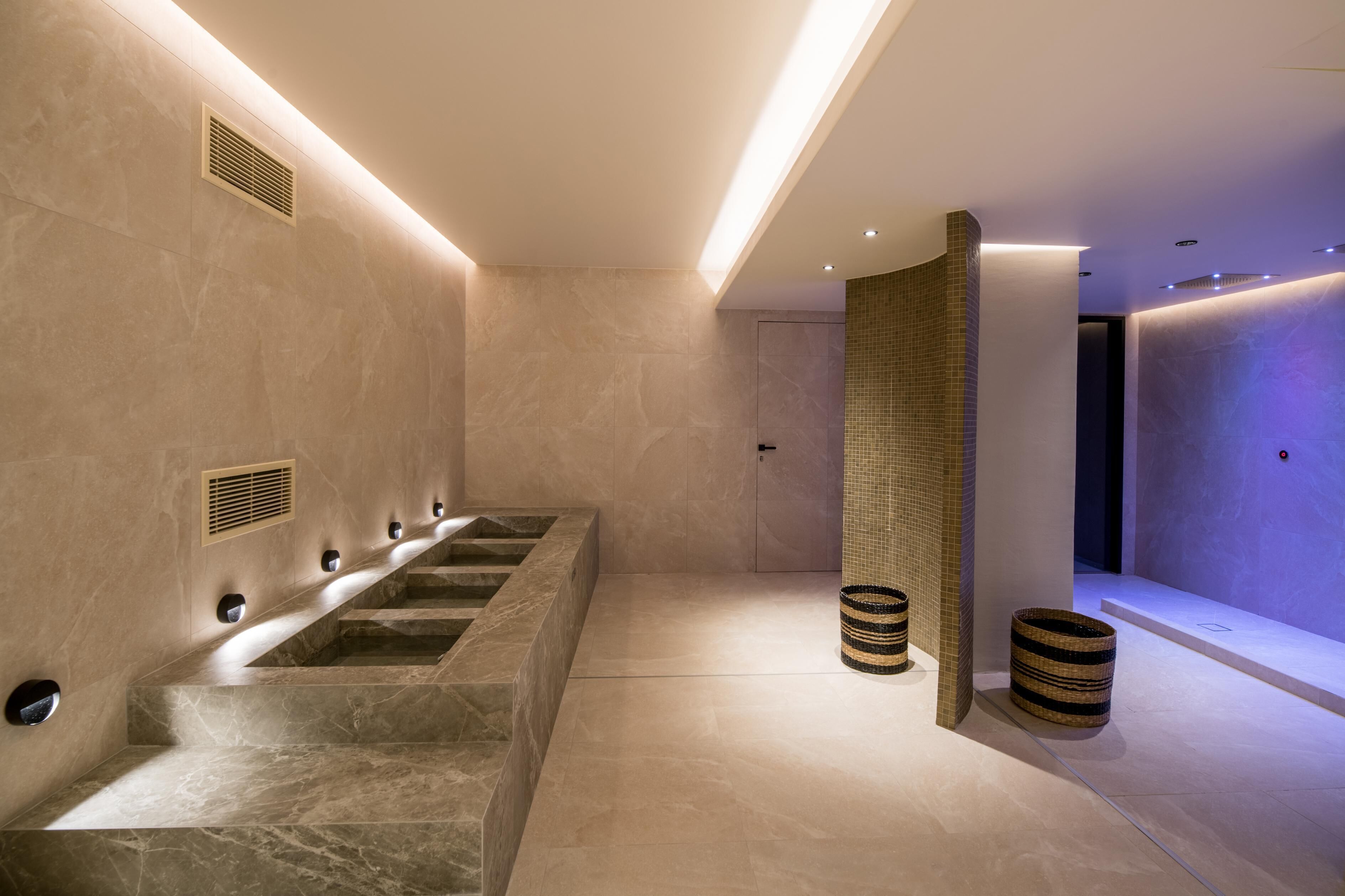 A modern bathroom with a marble sink, a shower area, and a tiled wall.