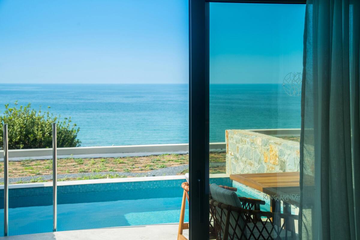 A view from a balcony overlooking a swimming pool and the sea.