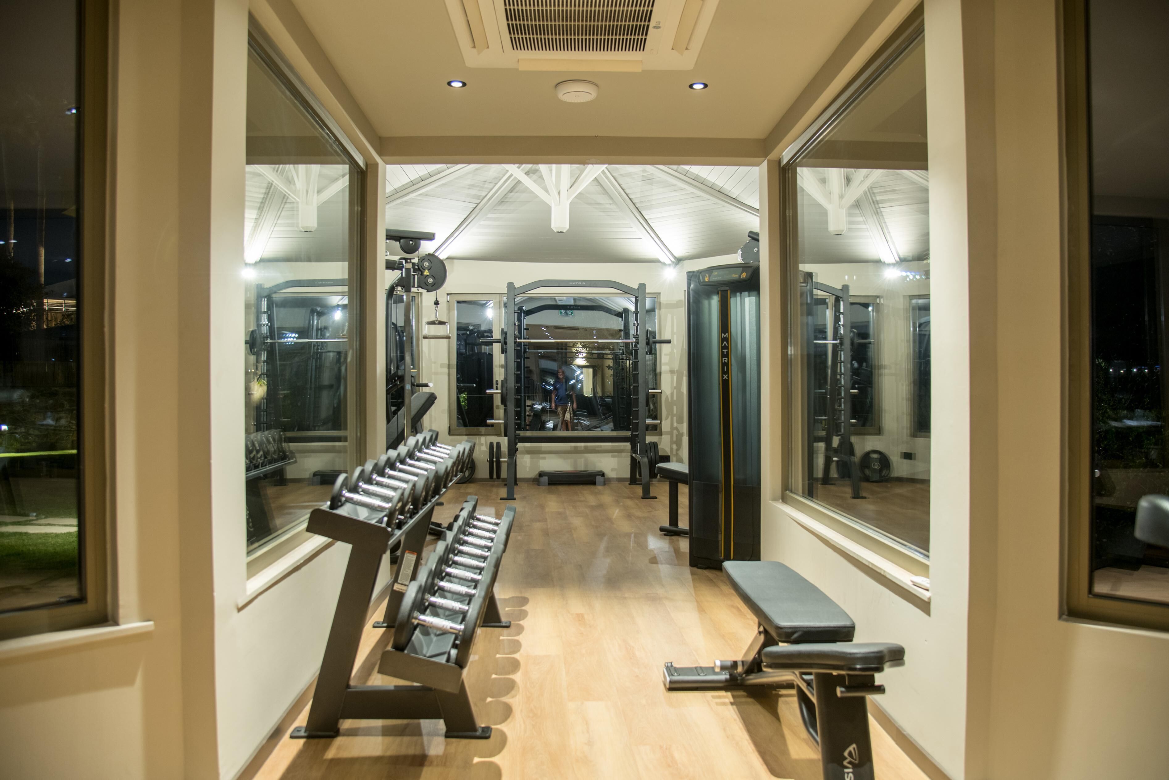 Un gimnasio con equipo de ejercicio, ventanas amplias y suelo de madera.