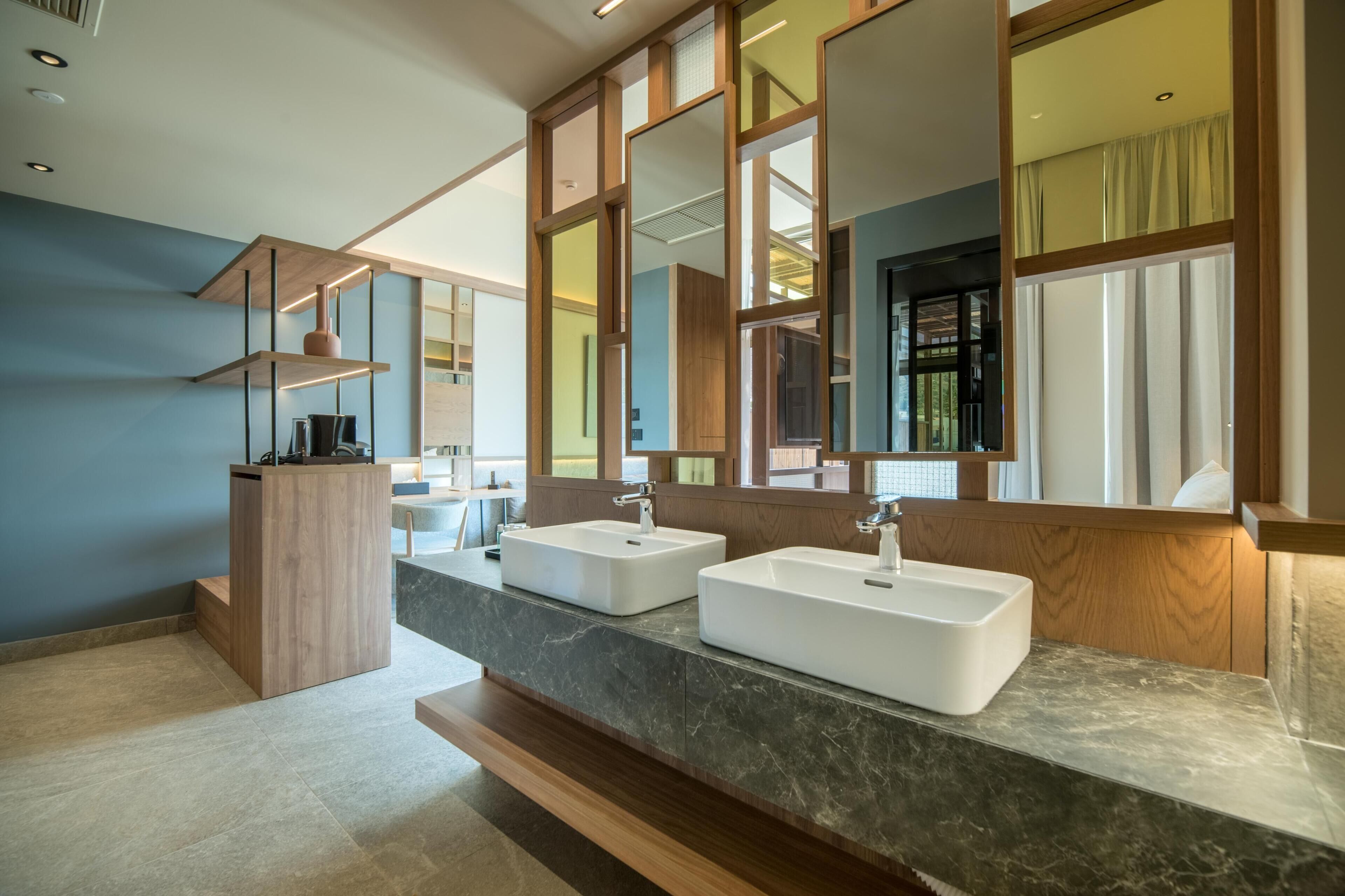 Un baño moderno con dos lavamanos, un tocador de madera y espejos grandes.