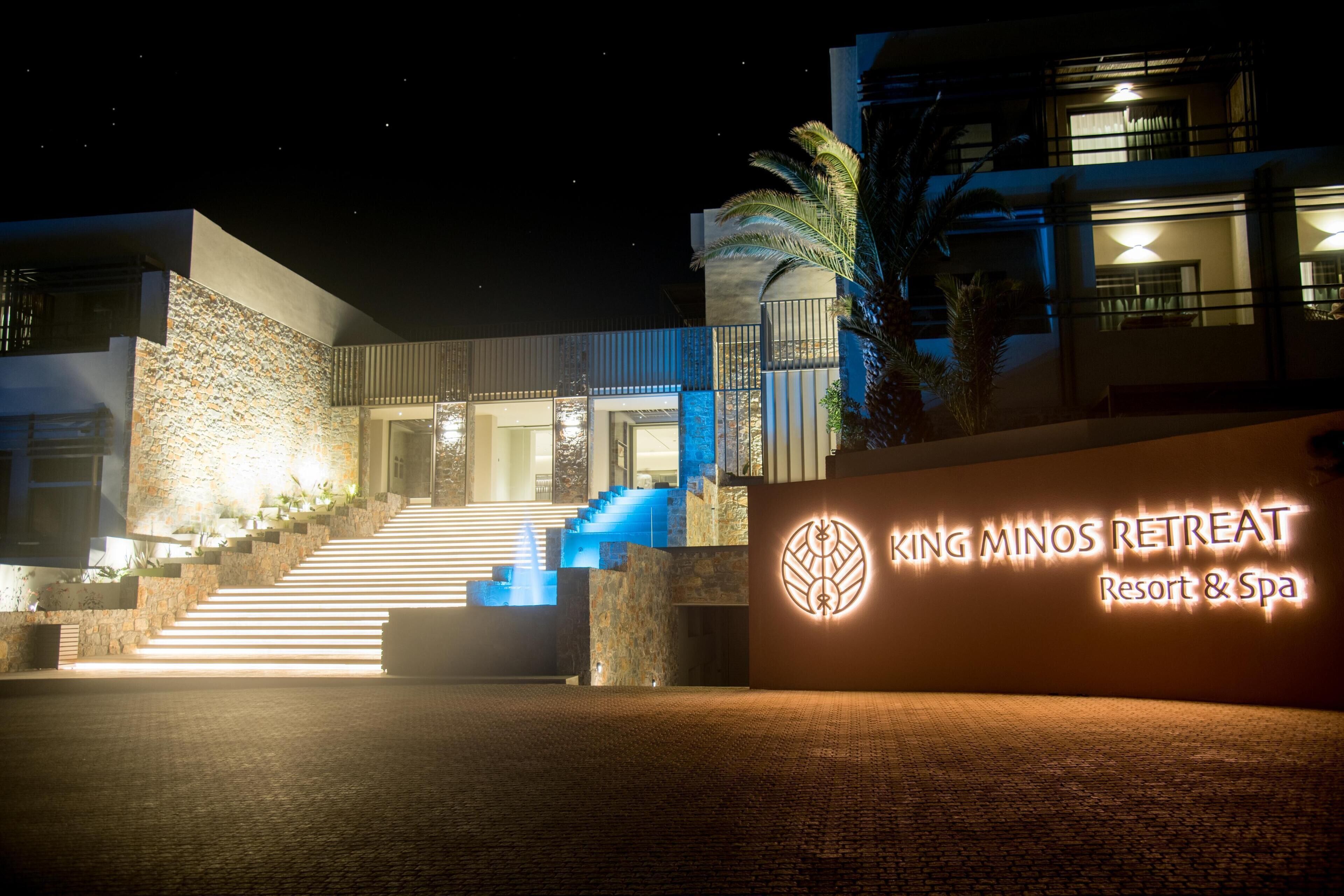 Ein modernes Gebäude mit Steinaußenwand, einer Treppe zum Eingang und einem Schild mit der Aufschrift "King Minos Retreat Resort & Spa".