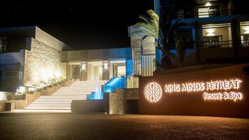 Un edificio moderno con fachada de piedra, una escalera que lleva a la entrada y un letrero que dice "King Minos Retreat Resort & Spa".